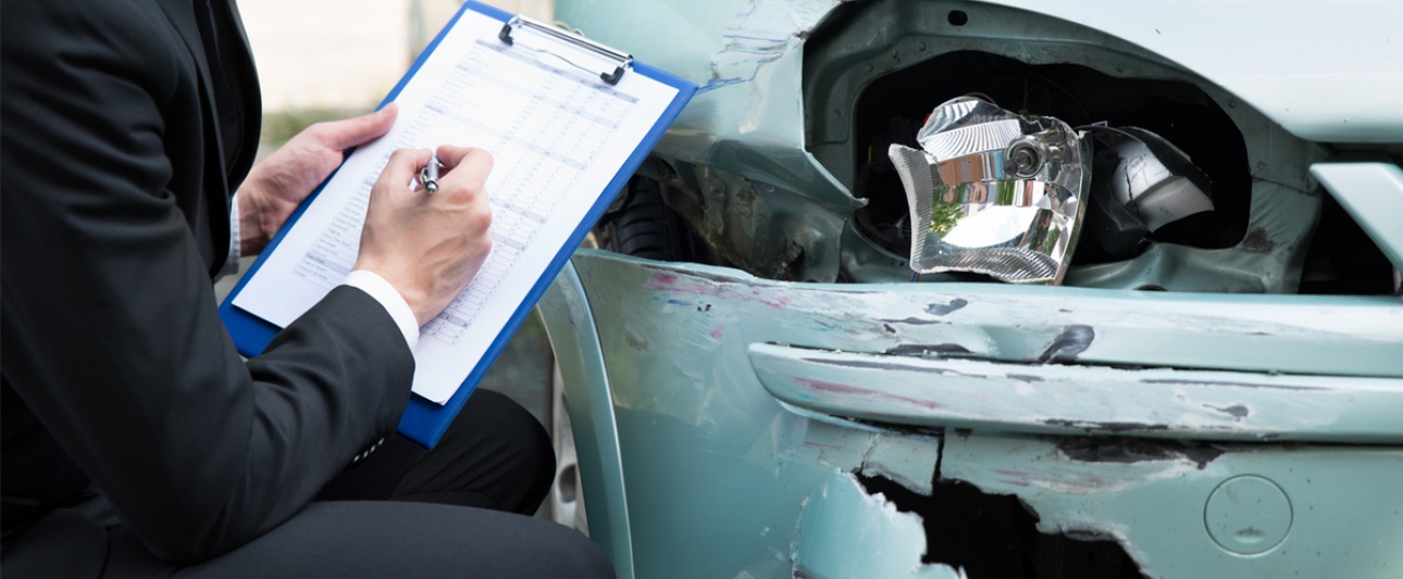 Ein Mann mit einer Checkliste nimmt die Schäden an einem Umfallfahrzeug auf